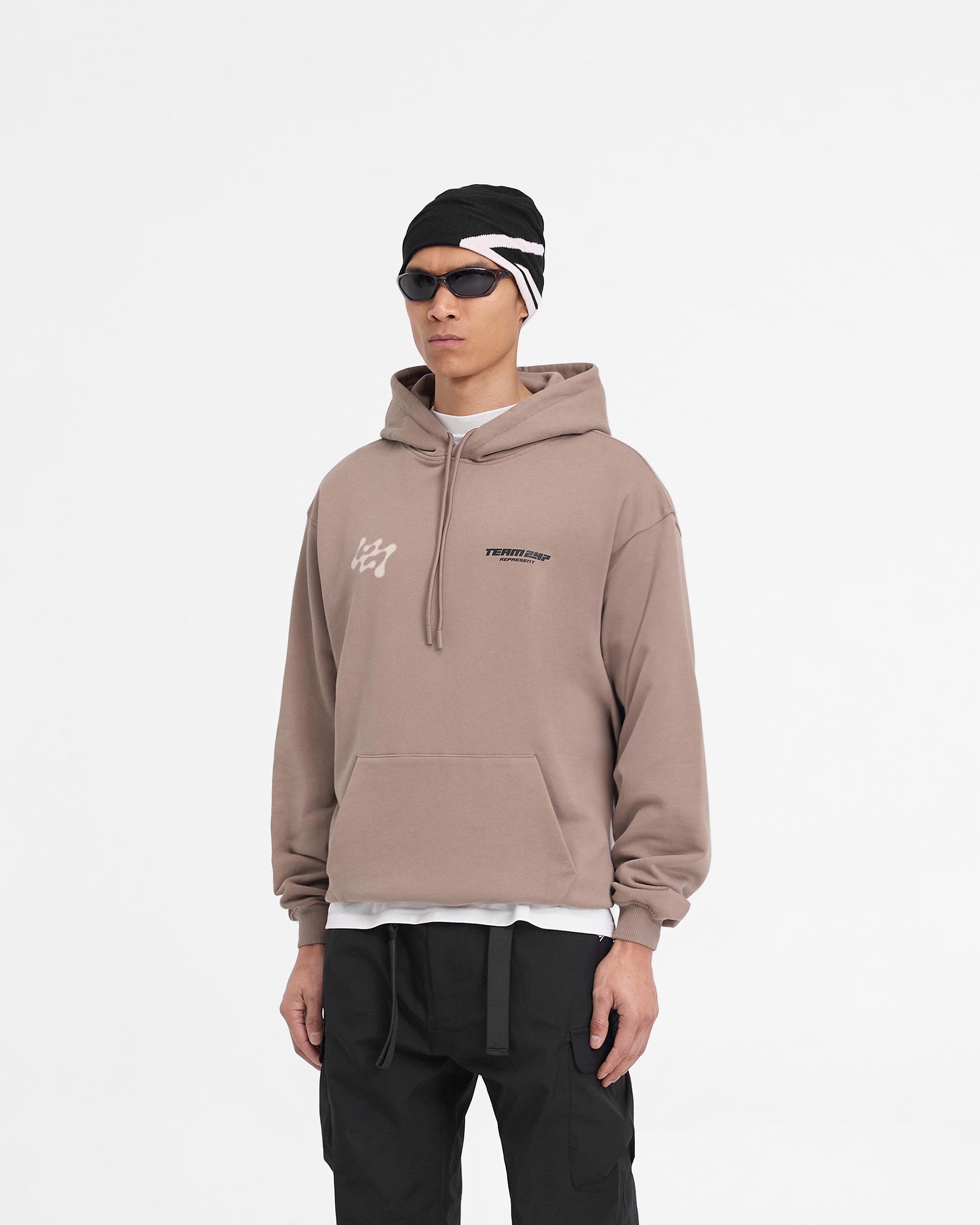Man wearing an oversized brown hoodie on a plain white background | 247 Future Terrains Oversized Hoodie in Umber | Heavyweight hoodie with ribbed hem and cuffs | 247 Hoodies | Represent Clo